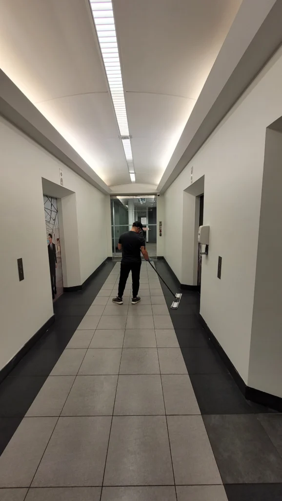 North York commercial cleaner cleaning an elevator hallway, wiping surfaces and maintaining a clean and professional building entrance area